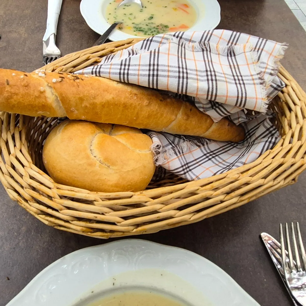 Brotkorb mit Salzstangerl und Semmel auf einem Tisch im Innenhof